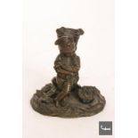 An early 20th Century bronze spill holder in the form of a young Breton boy near a basket of
