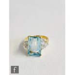 An 18ct hallmarked aquamarine and diamond ring, central emerald cut aquamarine, length 14mm, flanked