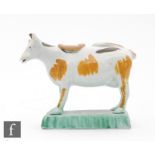 A late 18th to early 19th Century creamware cow creamer and cover, she with tan and brown patches,