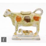 An early 19th Century Prattware type creamware cow creamer and cover with recumbent calf beneath,