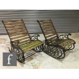 A pair of late 20th Century cast iron garden rocking chairs with decorative scroll side panels and