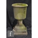 A stone urn or fountain pedestal of stepped vase form, with an octagonal faceted pedestal over an