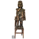 A 20th Century replica bronze figure of a young girl standing on a correction chair, height 46cm
