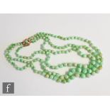 A triple graduated row of jade beads terminating in a 9ct hallmarked snap set with single bead,