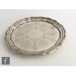 A hallmarked silver circular salver with engraved foliate decoration within raised, stepped plain