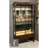 An early 20th Century mahogany shop display cabinet, the caddy shaped top above a bevelled brass