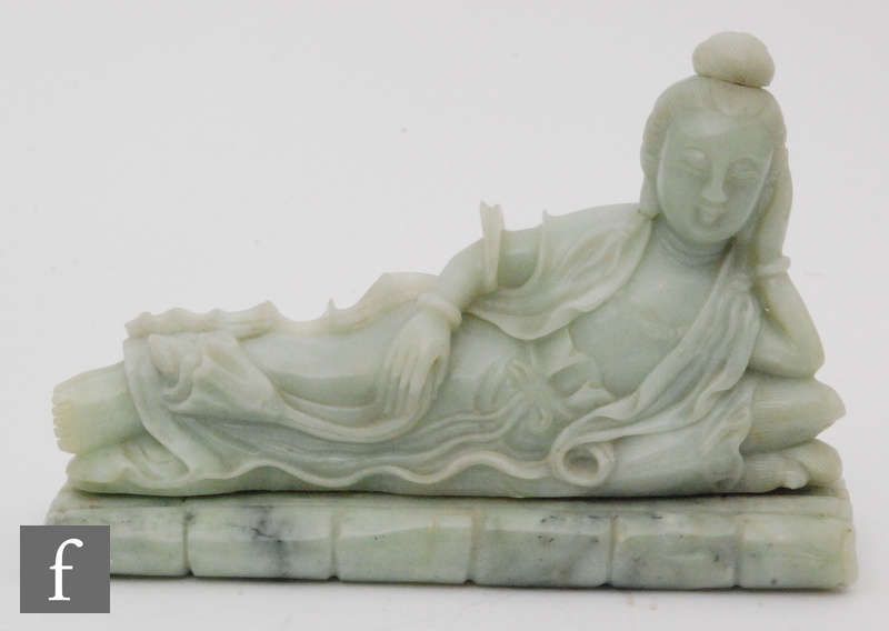 A Chinese green hardstone figure of Guanyin, modelled raised on a bamboo plinth, in reclining