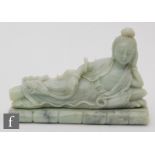 A Chinese green hardstone figure of Guanyin, modelled raised on a bamboo plinth, in reclining