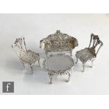 A hallmarked silver suite of miniature novelty furniture a settee, two dining chairs and an oval