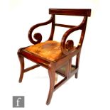 A late Regency period mahogany metamorphic library chair, with bar back over scroll arms, the