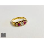 An 18ct hallmarked ruby and diamond boat shaped five stone ring, claw set stones to plain shoulders,