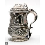 A George II hallmarked silver tankard and cover later embossed with foliate embossed and engraved
