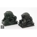 A pair of Chinese green hardstone carvings, each modelled as a shishi with foot raised, modelled