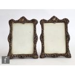 A pair of hallmarked silver easel photograph frames each with embossed foliate decoration and