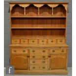 A Victorian style pine dresser, the upright section with an arched canopy over a plate rack and