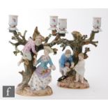 A pair of late 19th to early 20th Century Meissen twin branch candlesticks, the first with a lady