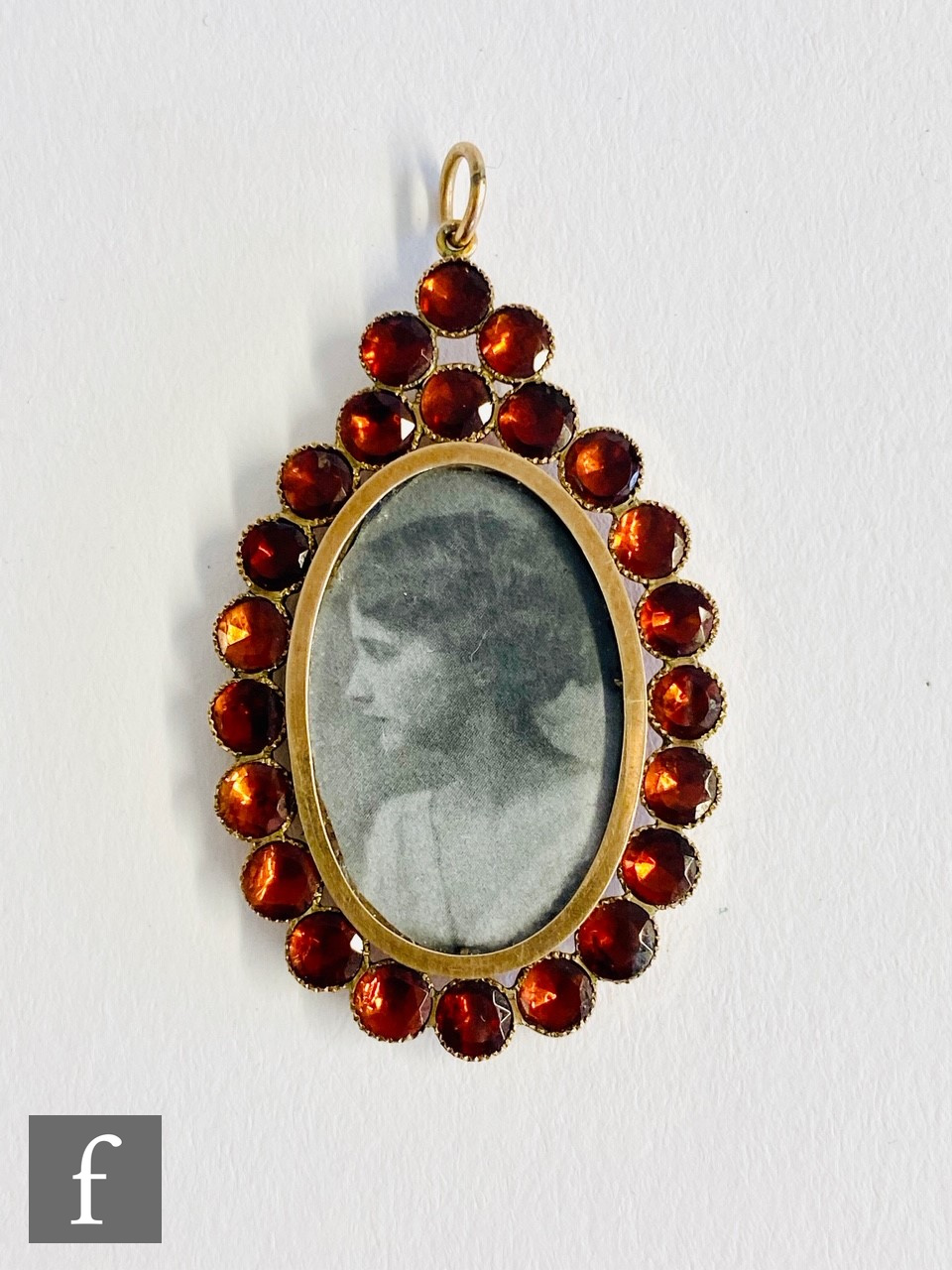 An early 20th Century 9ct pendant, central image of a young lady within an almadine garnet set