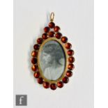 An early 20th Century 9ct pendant, central image of a young lady within an almadine garnet set