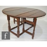 An 18th Century oak oval drop flap gate leg dining table on turned block legs and stretchers,