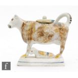 An early 19th Century pearlware cow creamer and cover with recumbent calf beneath, she with
