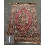 A Kashan rug, the central medallion on a wine ground within a multi running flower head border,