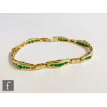 A 14ct emerald and diamond bracelet comprising seven panels of five graduated collar set emeralds