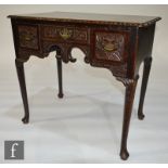A George III and later carved oak lowboy fitted with three frieze drawers, scroll arch on turned
