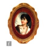A small early 20th Century oval porcelain plaque hand painted with a portrait of a young shepherd