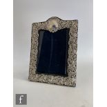 A hallmarked silver easel photograph frame with pierced foliate scroll decoration and vacant