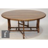 A 20th Century large oak circular gate-leg dining table, raised to a stretcher frame, 183cm in