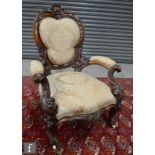 A Victorian armchair with exposed walnut frame, carved in relief with foliate detail over cabriole
