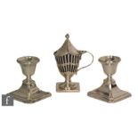 A pair of hallmarked silver squat candlesticks, canted square bases below circular sconces,
