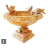 An alabaster circular pedestal bird bath mounted with birds to the rim, width 15cm, A/F.