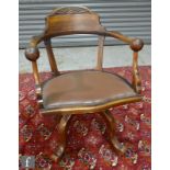 An Edwardian carved swivel office chair, leather inset seat on splayed legs.