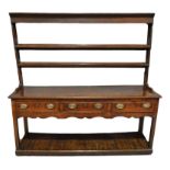 A George III oak dresser with later associated two-tier plate rack, fitted with three frieze drawers