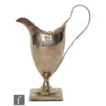 An 18th Century hallmarked silver pedestal cream jug, the plain body with punched beaded rim and