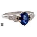 A platinum sapphire and diamond ring, central oval claw set sapphire with three diamond set to