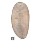 A Maasai hide shield, Kenya, of oval form with stitched outer border and with a wooden rib handle,