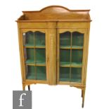 An Edwardian marquetry inlaid mahogany display cabinet, enclosed by a pair of bar glazed doors below