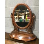 A Victorian mahogany toilet swing mirror of oval form, raised to twin acanthus carved supports