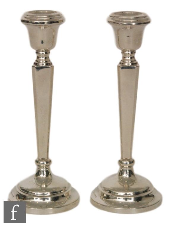 A pair of hallmarked silver candlesticks, circular bases below tapering square slender columns and