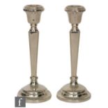 A pair of hallmarked silver candlesticks, circular bases below tapering square slender columns and