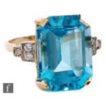An 18ct blue topaz and diamond ring, emerald cut claw set topaz with three diamonds to each