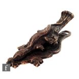 A cast bronze desk clip modelled as a lizard to a leafy bough over a shaped base with matched