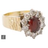 A 1970's 18ct ruby and diamond cluster ring, central oval ruby length 8mm within a ten stone