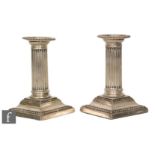 A pair of hallmarked silver Corinthian column candlesticks of typical each, each with circular