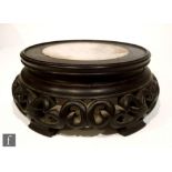 A Chinese hardwood stand of circular form, with an inset white marble top over a fretwork scroll