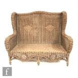 A contemporary wicker settle in the Arts and Crafts style, with curved arms and back with a