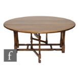 A 20th Century large oak circular gate-leg dining table, raised to a stretcher frame, 183cm in