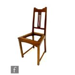 An Arts and Crafts oak side chair in the manner of Liberty & Co, with pierced spade or seed pod